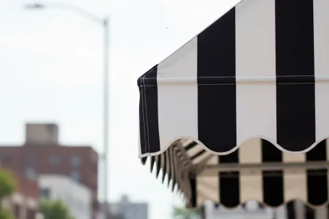 Detalle de limpieza de toldos de lona con rayas blancas y negras en Barcelona