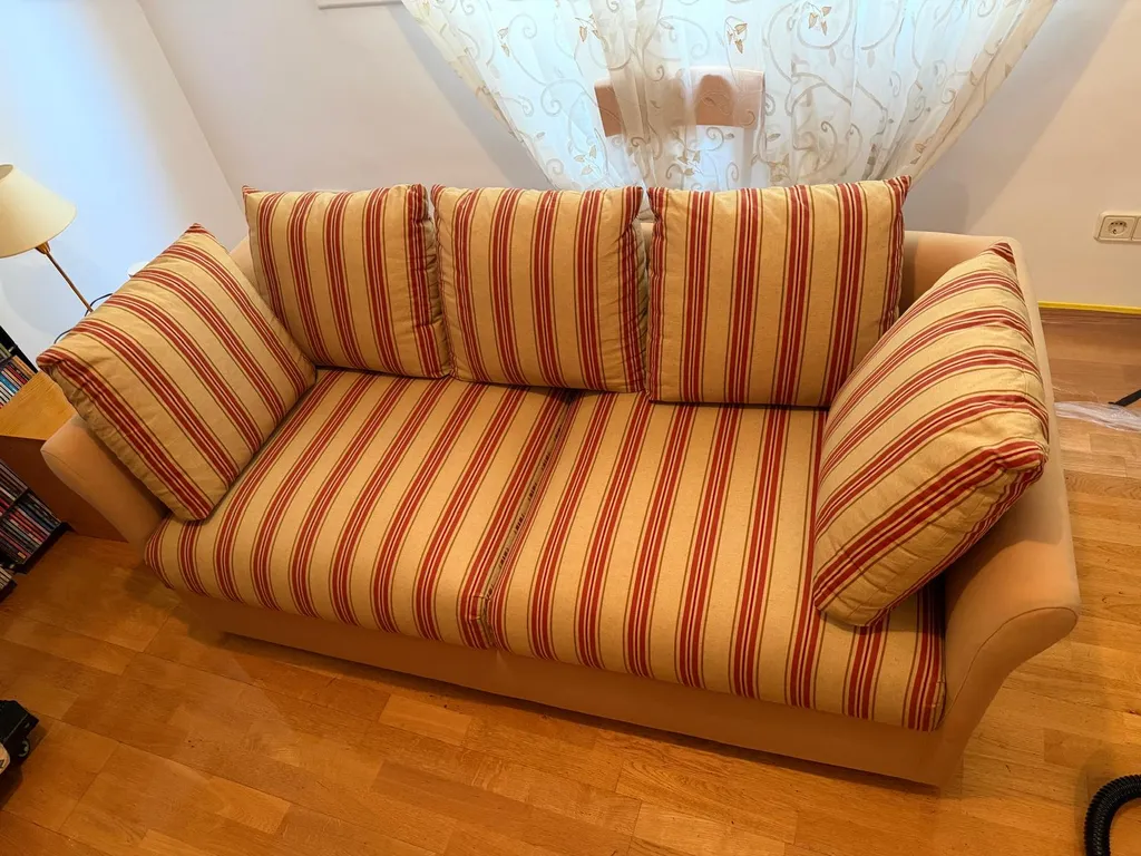 Sofá antiguo a rayas con tejido oscurecido por el polvo antes de un tratamiento profesional cuidadoso para evitar la migración de color