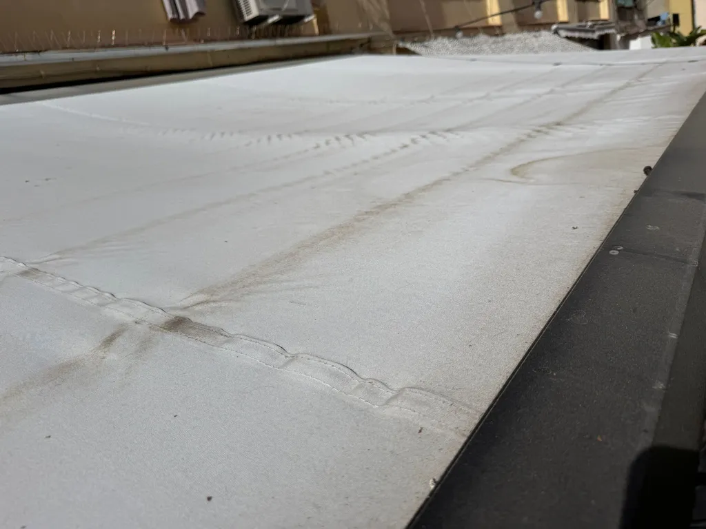 Detalle de un toldo de terraza muy sucio con moho y manchas incrustadas antes de la limpieza