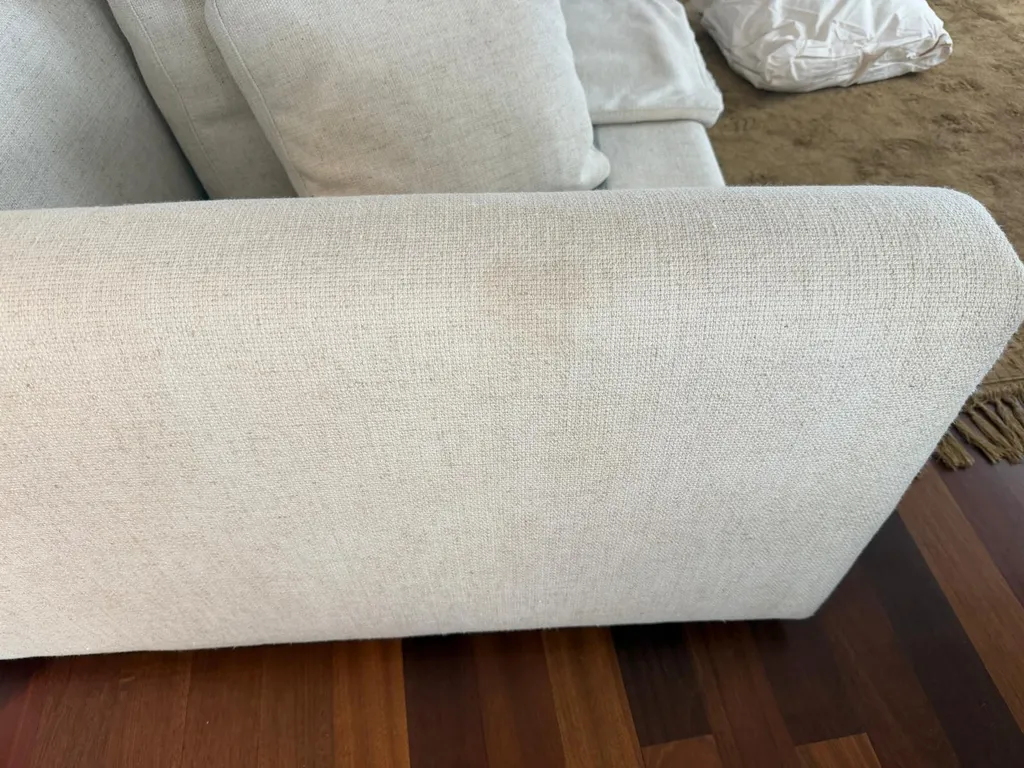 Funda de sofá de diseño arruinada por encogimiento y pérdida de color tras una limpieza no profesional