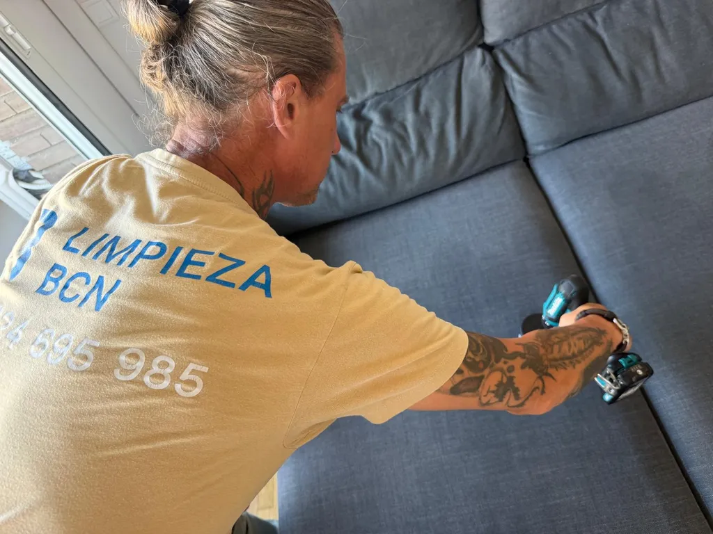 Técnico profesional de Limpieza BCN con uniforme limpiando un sofá a domicilio en Barcelona