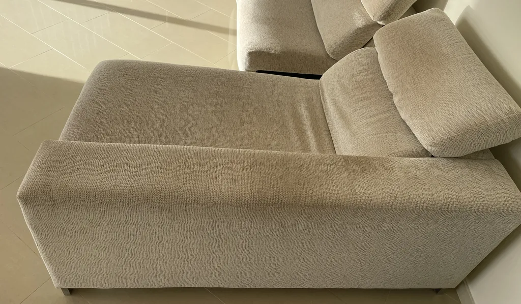 Manchas de rozadura en el reposabrazos del sofá | Limpieza BCN Reposabrazos de un sofá de tela beige con una mancha oscura de grasa corporal y rozadura por el uso diario