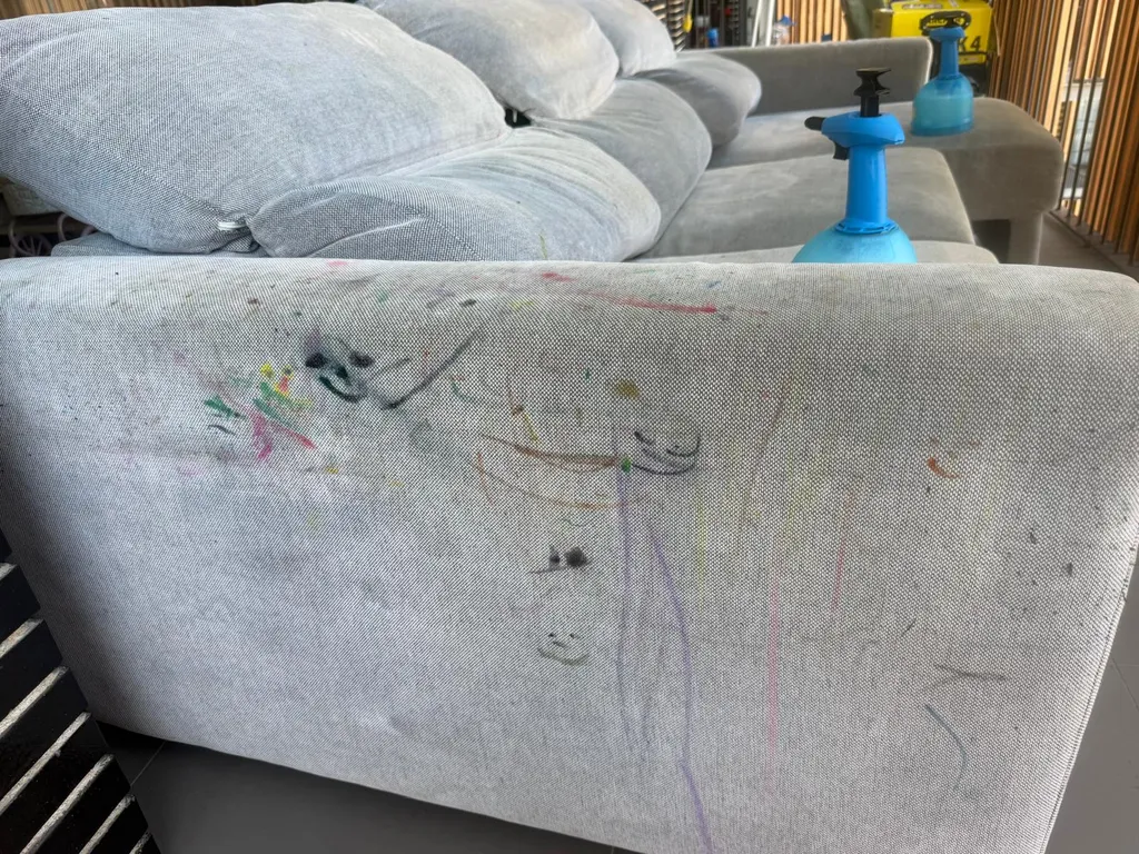 Dos pulverizadores de pre-lavado con química profesional sobre el sofá gris antes de limpiar rotulador del sofá