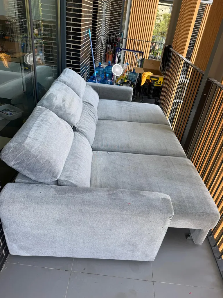 Vista completa de un sofá de tela gris claro perfectamente limpio y desinfectado en el salón