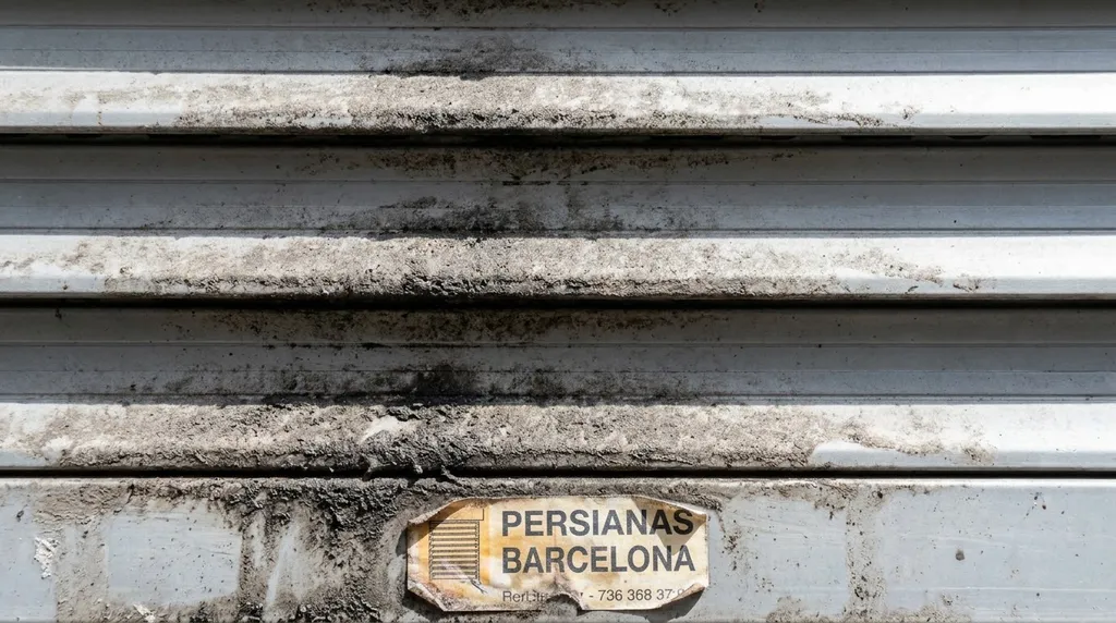 Persiana de plástico muy sucia de hollín urbano | Limpieza BCN Detalle de la cara externa de una persiana de PVC sucia de polvo negro y hollín en Barcelona