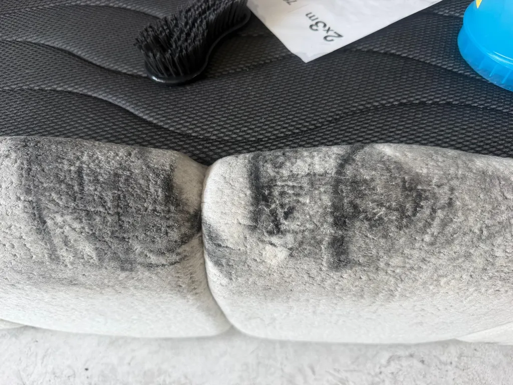 Detalle macro de hollín graso y ceniza negra incrustada en la tapicería de tela de un cabecero de cama